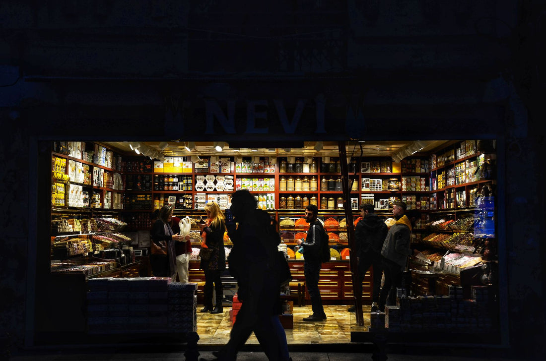 A vibrant, illuminated street shop filled with people engaging in nighttime shopping.